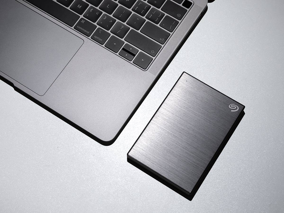 Image of backup hard drive sitting next to an Apple laptop
